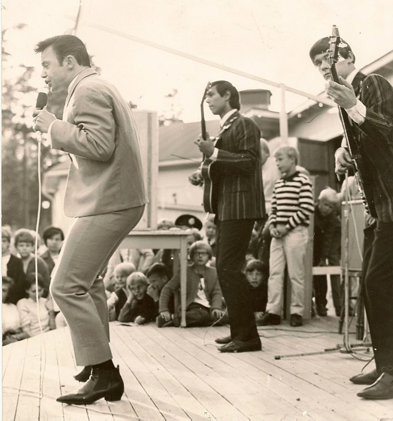 Jerry Williams sjunger på scen medan basisten Mike Watson spelar Gibson EB3 i en svensk folkpark 1965.
